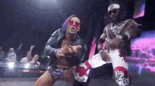 a couple of wrestlers are standing next to each other in a wrestling ring .