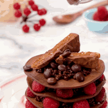 a stack of chocolate pancakes with raspberries and m & ms on top