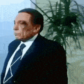 a man in a suit and tie is listening to music with a plant in the background .