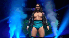 a wrestler in a peacock costume is walking through a tunnel of smoke .