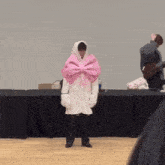 a person wearing a white coat with a pink bow on the front
