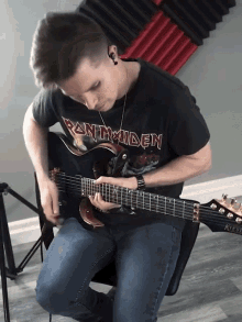 a man wearing a iron maiden shirt plays a guitar