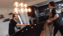 two men are playing pool in a kitchen and one of them is wearing a shirt that says ' i love you '