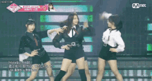 a group of girls are dancing on a stage with a mnet logo behind them