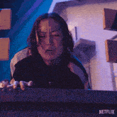 a netflix advertisement shows a man in a green jacket reaching over a railing