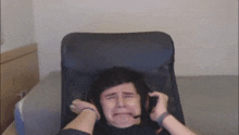 a man is sitting in a chair with headphones on and making a face .