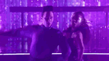 a man and a woman are dancing together on a stage in a purple light .
