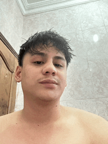 a shirtless man is standing in front of a white tiled wall