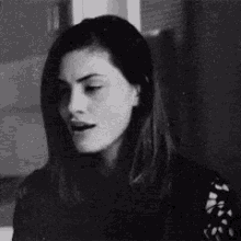 a black and white photo of a woman making a funny face with her mouth open .