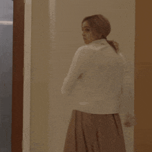 a woman in a white dress is standing in a doorway with frosted glass
