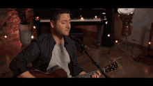 a man playing an acoustic guitar in front of a mirror