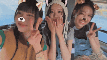 three girls are posing for a picture and one has a cat hat on her head