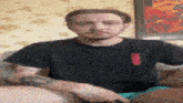 a man in a black shirt is sitting on a couch .