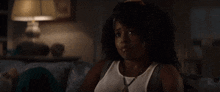 a woman with curly hair is sitting on a couch in a dark room .