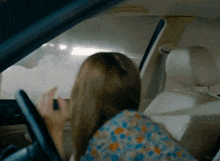a woman is sitting in a car with the word kegler on the bottom right