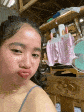 a woman is making a funny face while sitting in front of a fan .