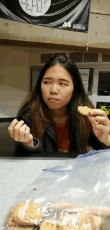 a woman is eating a cookie in front of a depot banner