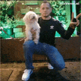 a man kneeling down holding a small white dog with pixverse ai written on the bottom right