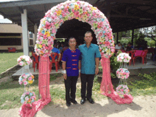 two men standing in front of a pink flower arch