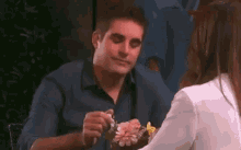 a man is sitting at a table with a woman and holding flowers .