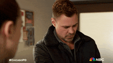 a man in a black jacket is talking to a woman in a nbc chicagopd ad