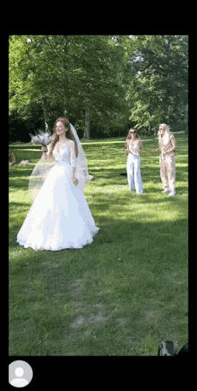 a bride in a white dress is standing in a grassy field