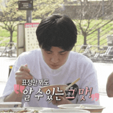 a man in a white shirt is eating a meal with chopsticks
