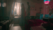 a man and a woman are standing in a bedroom with a pink lamp