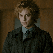 a man with curly blonde hair is wearing a black jacket