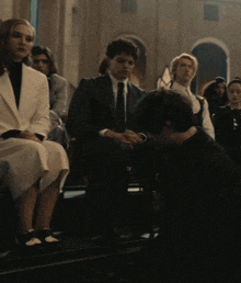 a group of people are sitting in a dark room with one man kneeling down