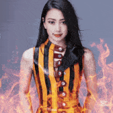 a woman in a yellow and black striped top is surrounded by fire