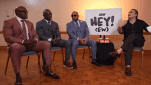 four men sit in front of a sign that says hey ( ew )