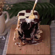 a piece of cake on a wooden cutting board with a fork sticking out of it