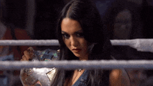 a woman is standing in a wrestling ring holding a championship belt