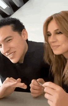 a man and a woman are sitting at a table holding a pen and smiling .