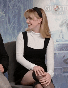 a woman is sitting in front of a ghostbusters poster