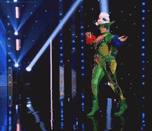a woman in a green and yellow outfit is walking on a stage with a tumblr logo in the background