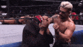 a shirtless wrestler is fighting another wrestler in a wrestling ring with the abm logo in the background