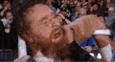 a man with a beard is being punched in the face by another man in a wrestling ring .