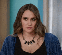 a woman wearing a black necklace and a blue sweater
