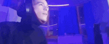 a man is screaming in a dark room with purple lights behind him .