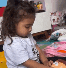 a little girl is playing with a toy story doll on the floor .