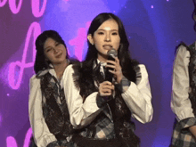 a girl is holding a microphone in front of a purple background