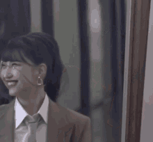 a woman wearing a suit and tie is smiling and looking at the camera