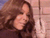 a woman is standing in front of a brick wall holding a rope .