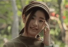 a young woman wearing a hat and a watch is smiling and looking at the camera .