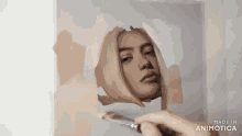 a person is painting a picture of a woman 's face with a brush .
