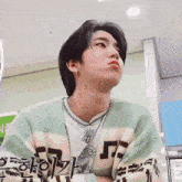 a young man wearing a green and white striped sweater with chinese writing on the sleeves
