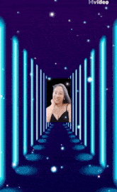 a woman in a black top is standing in a tunnel of blue lights .