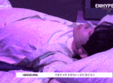 a person laying on a bed with purple sheets and a sign that says enhype